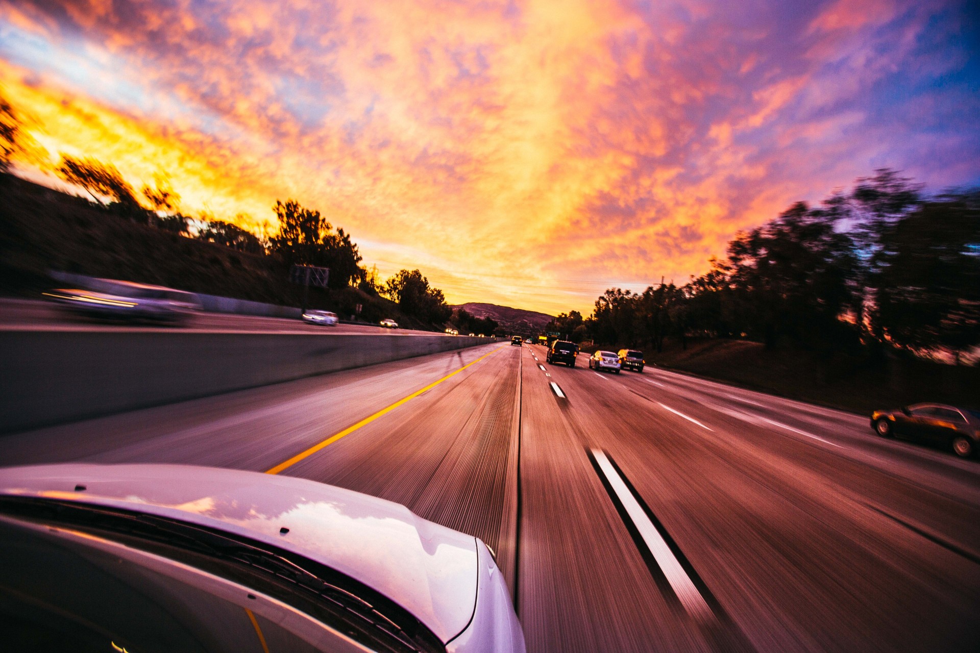 Cars driving down road with sunset